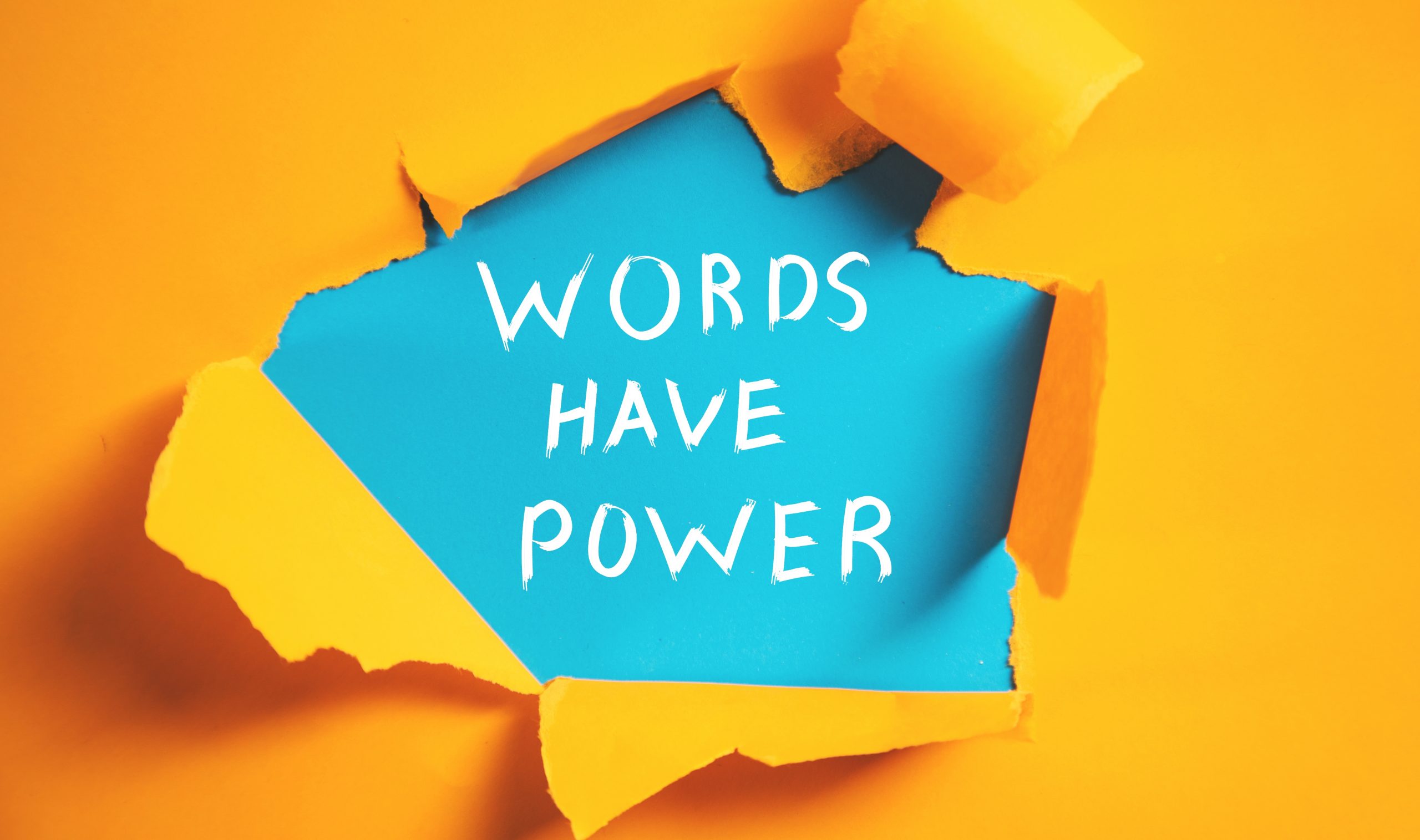 Bright orange background with torn paper revealing the phrase "WORDS HAVE POWER" in bold white letters on blue.