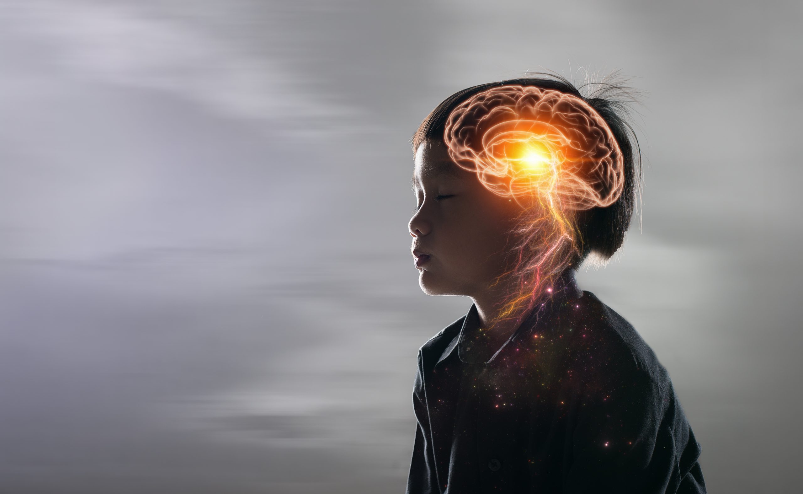 A child in profile with a glowing brain illustration, symbolizing creativity and thought against a blurred background.