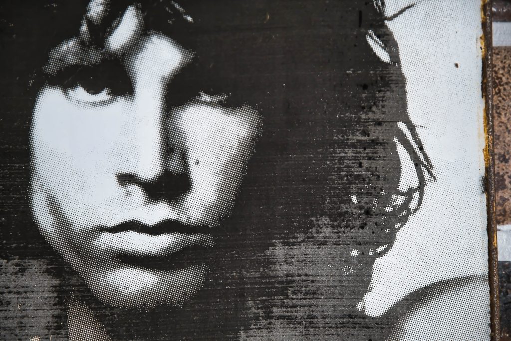 Close-up of a monochrome portrait featuring a man's intense gaze and tousled hair, with a textured background.