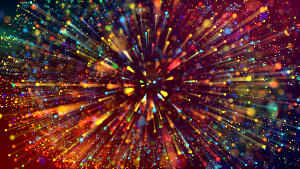 Colorful bursts of light and particles radiate outward against a dark background, creating a vibrant, dynamic effect.