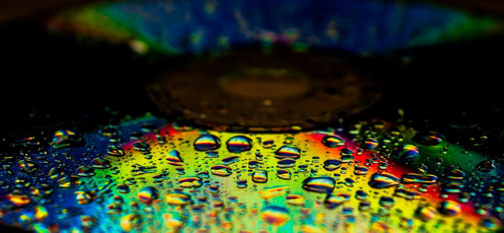 Colorful droplets of water on a reflective surface, creating a vibrant, abstract pattern.
