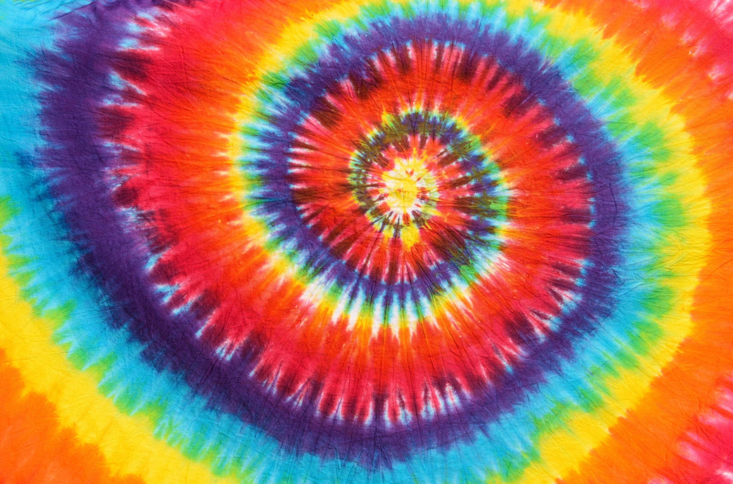 Colorful tie-dye pattern featuring concentric circles in vibrant hues of red, orange, yellow, green, blue, and purple.