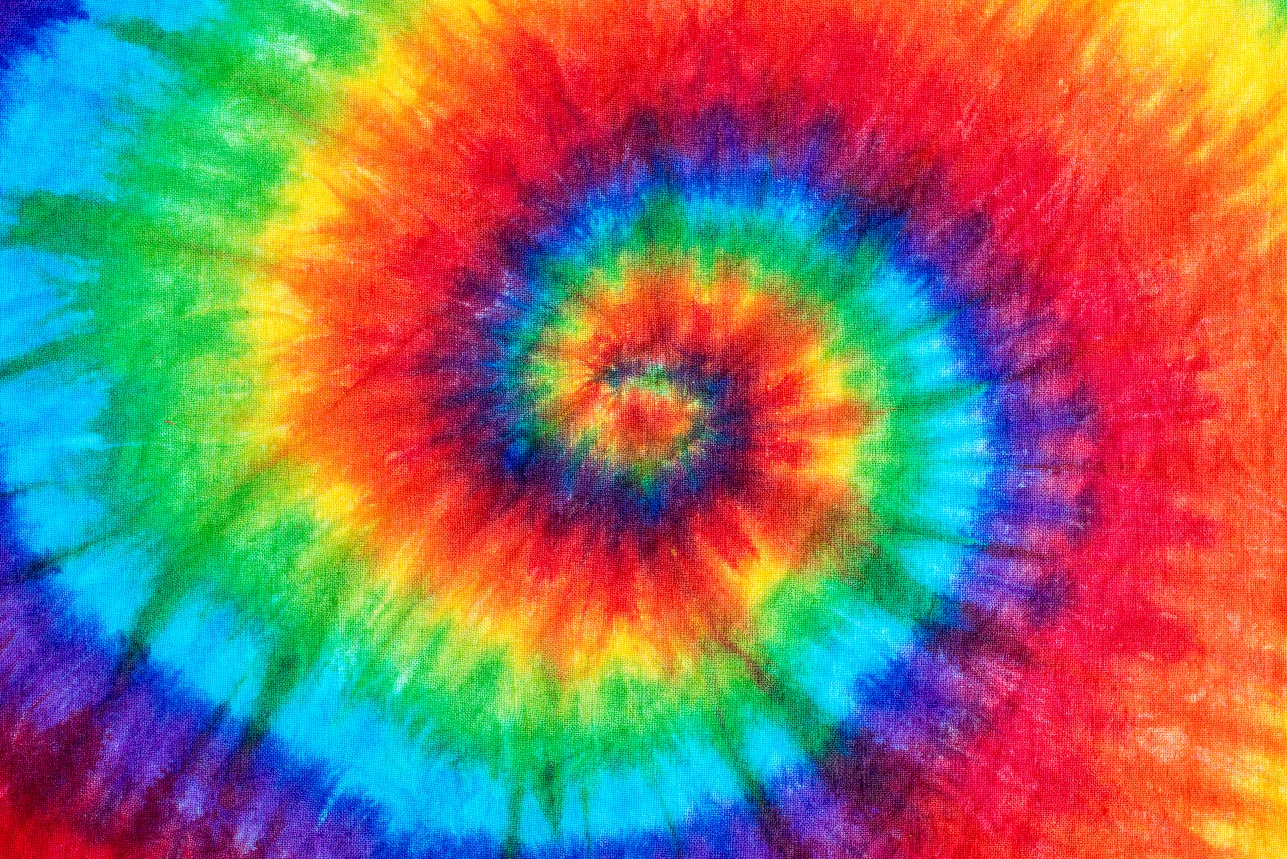 Colorful tie-dye pattern featuring vibrant swirls of red, orange, yellow, green, blue, and purple.