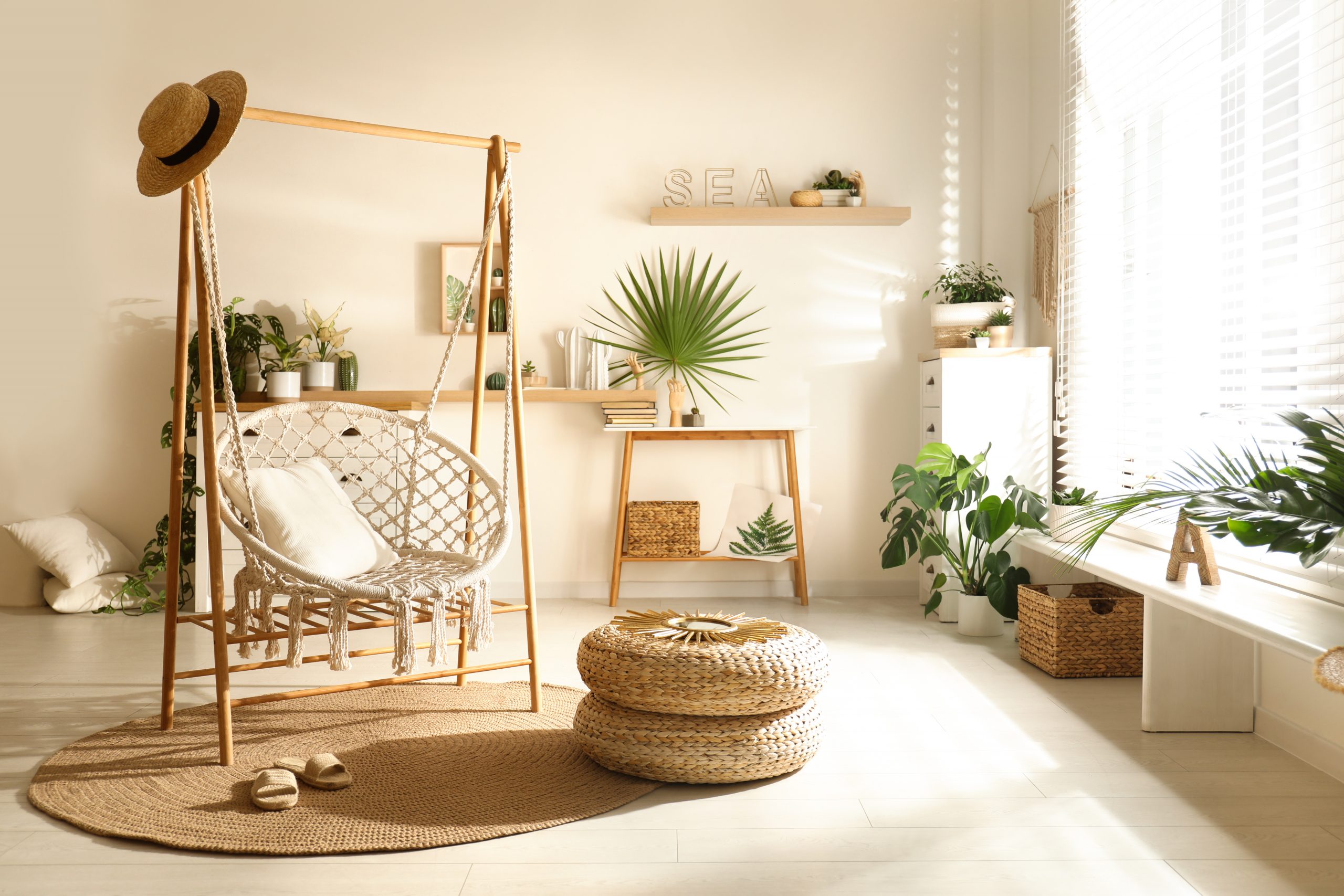 Cozy indoor space with a hanging chair, natural decor, plants, and warm sunlight filtering through the windows.