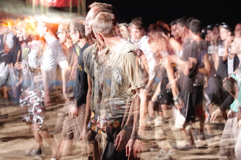 A crowd of people dancing at night, with motion blur creating a dynamic, energetic atmosphere.