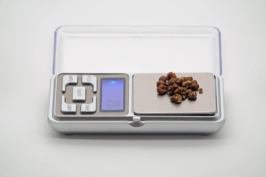 Digital scale displaying 6.99 grams with small brown stones on the weighing platform.