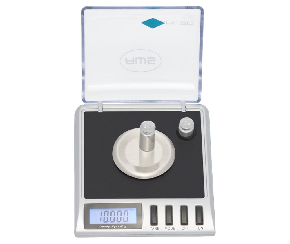 Digital scale with a stainless steel platform, calibration weights, and a clear lid, displaying a weight of 100.00 grams.