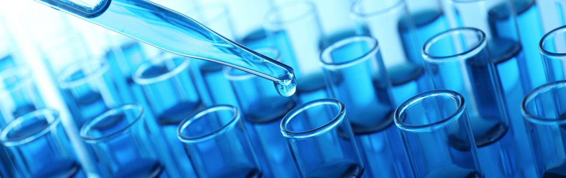 A dropper releasing a liquid into a row of blue test tubes.