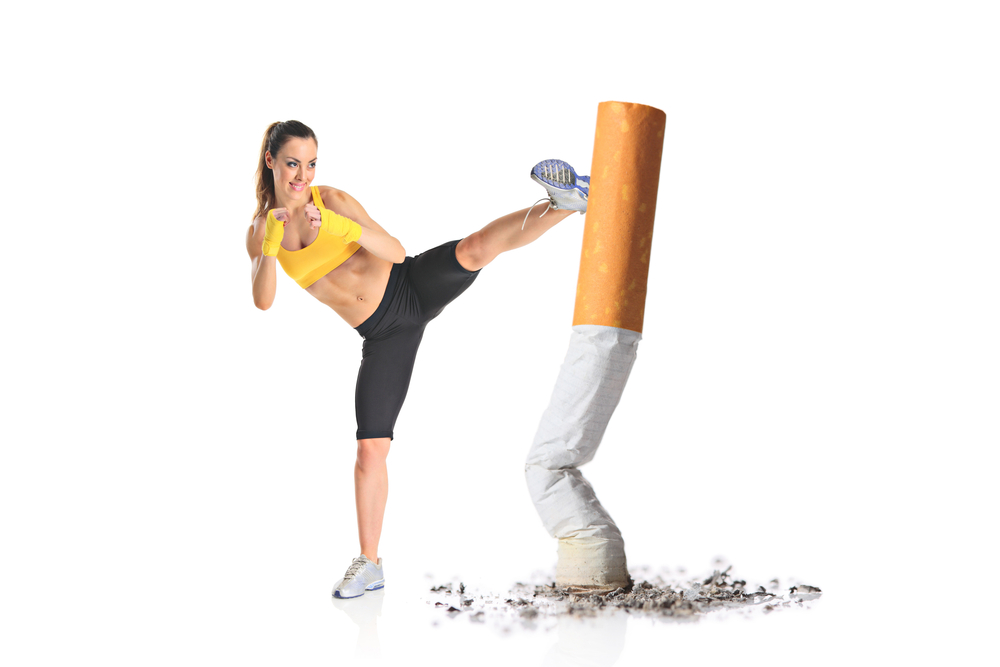 A fit woman kicks a giant cigarette, symbolizing the fight against smoking, with ashes scattered below.
