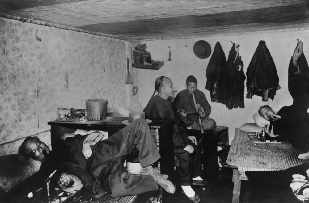 Five men relax in a dimly lit room, with traditional clothing and simple furnishings, creating a cozy atmosphere.