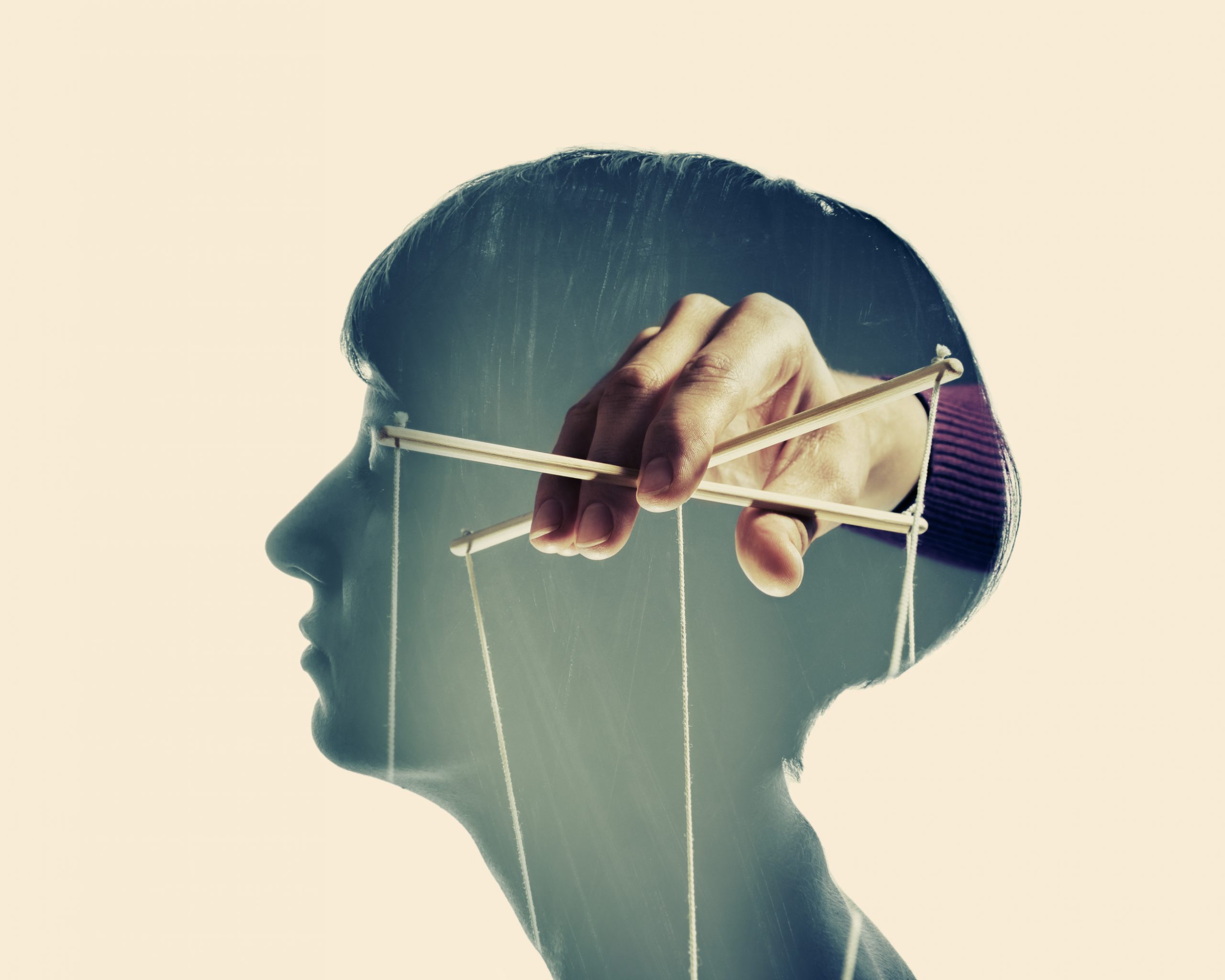 A hand manipulates puppet strings above a silhouette of a person's head, symbolizing control and influence.