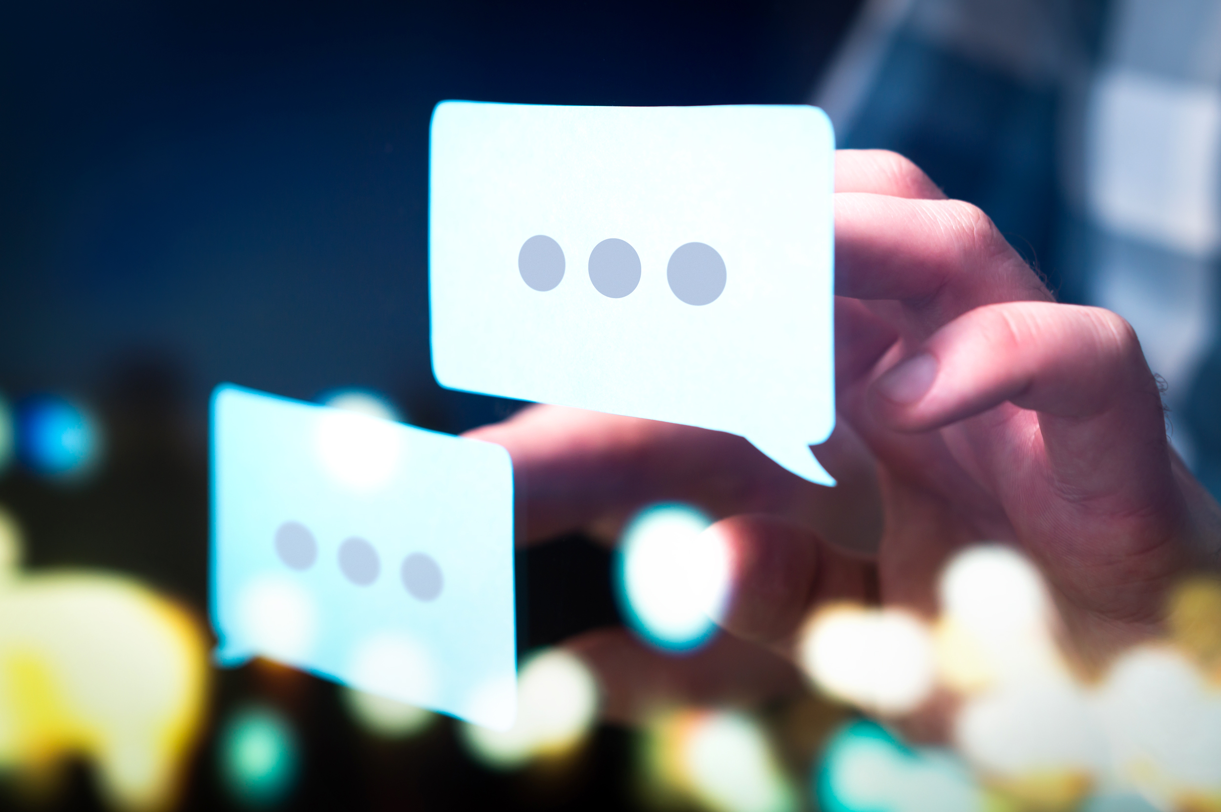 A hand reaches toward glowing speech bubbles with three dots, suggesting an ongoing conversation.