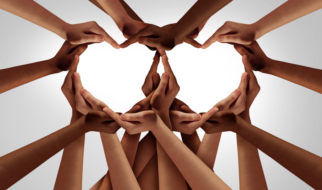 Hands of various skin tones forming a heart shape against a light background, symbolizing unity and love.