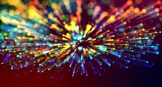 Colorful bursts of light radiate outward against a dark background, creating a dynamic, vibrant explosion effect.