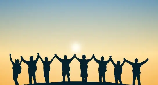 Silhouetted figures holding hands against a sunset, symbolizing unity and togetherness.