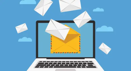 A laptop screen displays an open envelope with several flying envelopes against a blue sky background.