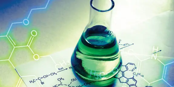 Green liquid in a glass flask on a sheet of paper with chemical formulas and molecular structures.