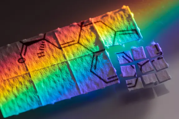 Colorful rainbow reflection on blotter paper with chemical structures drawn in black ink.