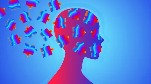 Silhouette of a head with colorful puzzle pieces dispersing against a blue gradient background.