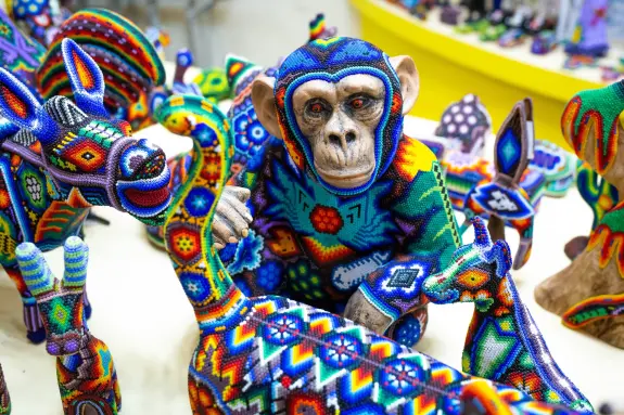Colorful beaded sculptures of animals, featuring a monkey in a vibrant sweater, surrounded by intricate designs.