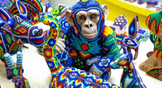Colorful beaded sculptures of animals, featuring a monkey in a vibrant sweater, surrounded by intricate designs.