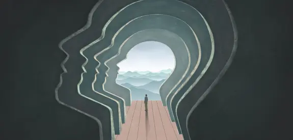 Silhouettes of human faces in profile, leading to a figure standing on a platform with distant mountains and a cloudy sky.