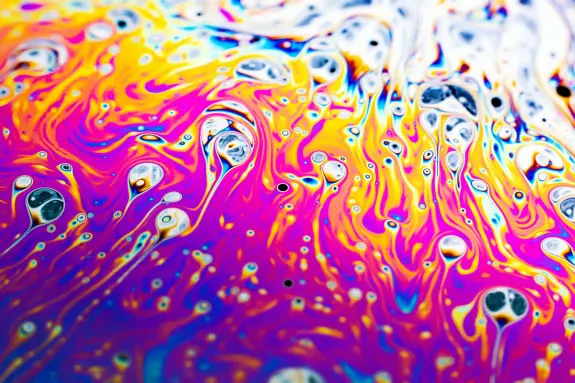 Vibrant swirls of purple, orange, and blue create a mesmerizing abstract pattern with bubbles throughout.