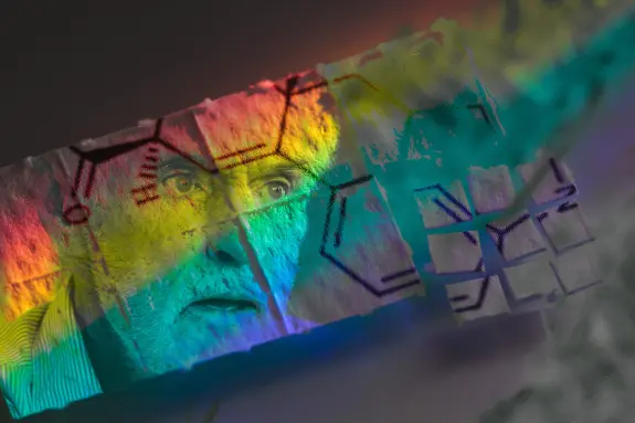 An elderly man's face is overlaid with colorful chemical structures and abstract patterns, creating a surreal effect.