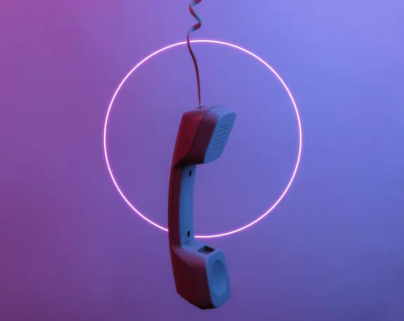 Hanging vintage telephone receiver surrounded by a glowing pink circular light against a gradient purple background.