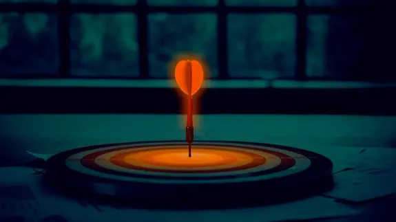 A glowing dart embedded in the center of a target, set against a dark, blurred background.