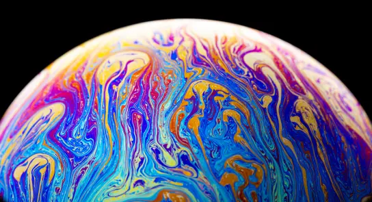 A colorful soap bubble with swirling patterns of blue, purple, and orange against a black background.