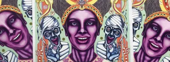 Vibrant mural featuring a woman with striking features, flanked by ghostly figures and intricate patterns.