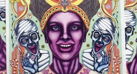Vibrant mural featuring a woman with striking features, flanked by ghostly figures and intricate patterns.