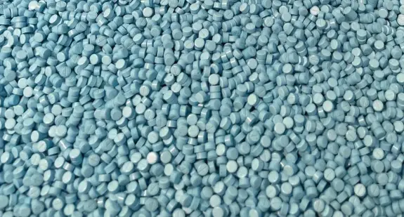 A dense spread of small, round, light blue tablets covering a flat surface.