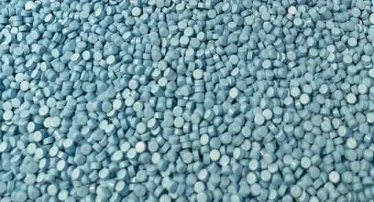 A dense spread of small, round, light blue tablets covering a flat surface.