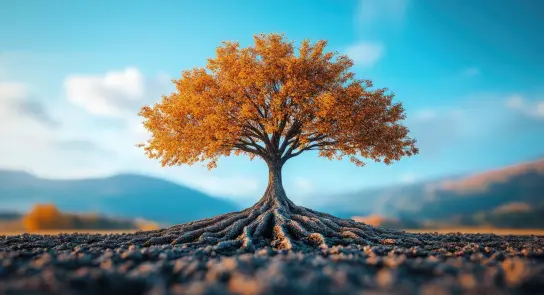 A vibrant orange tree stands alone, its roots sprawling across the ground against a backdrop of blue sky and mountains.