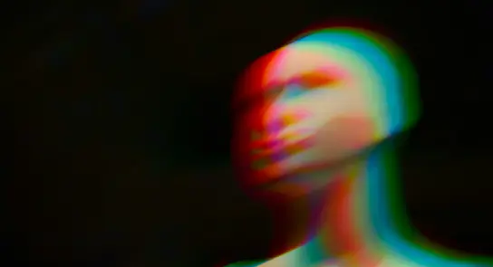 A blurred mannequin head with colorful, distorted lighting against a dark background.