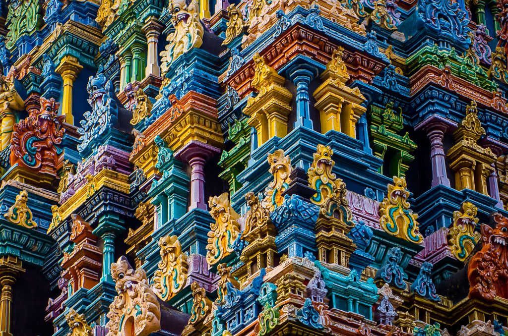 Intricate temple facade adorned with vibrant colors and detailed sculptures of deities and mythical creatures.
