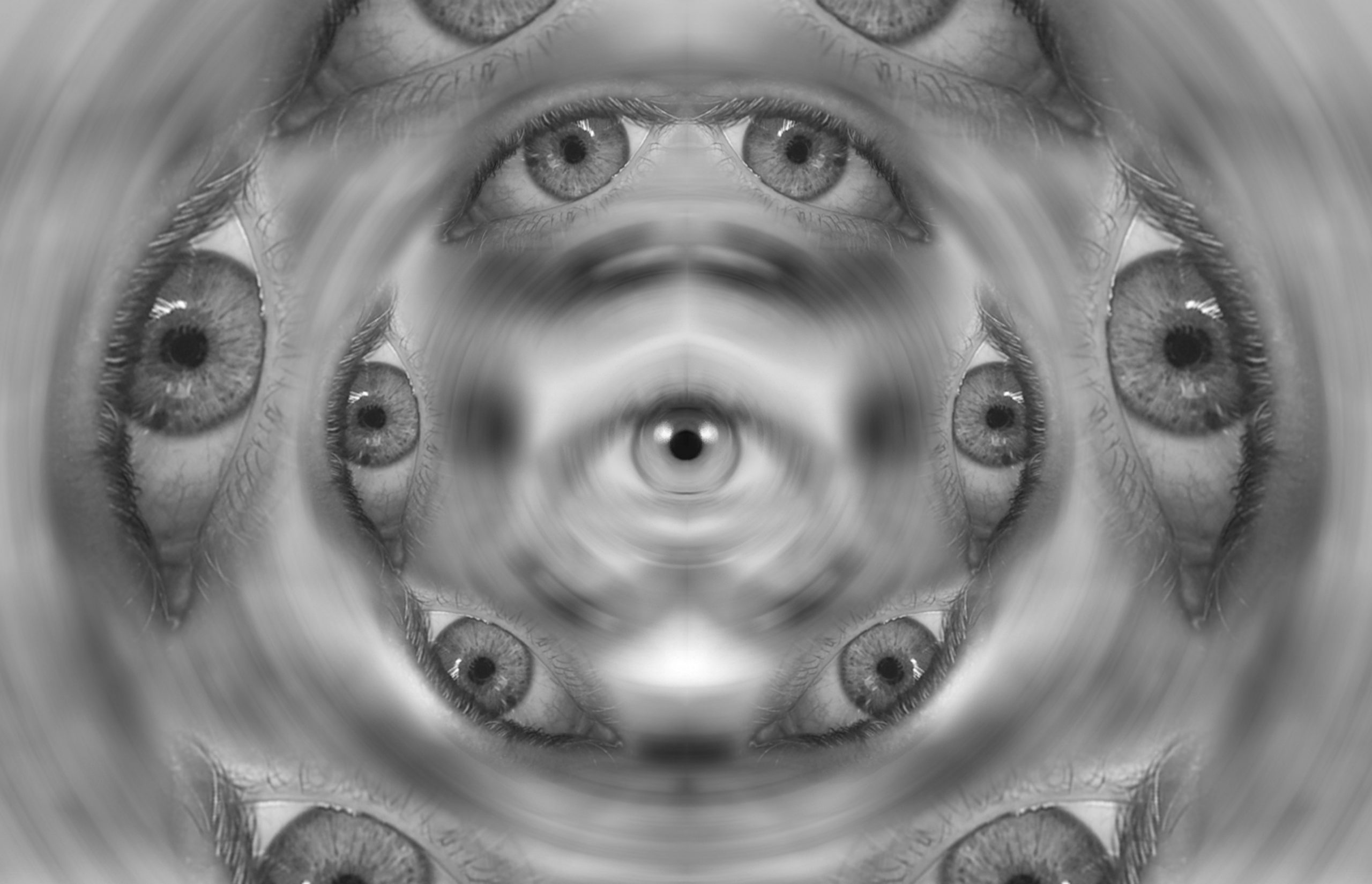 A kaleidoscopic pattern of multiple human eyes in grayscale, creating a mesmerizing, swirling effect.