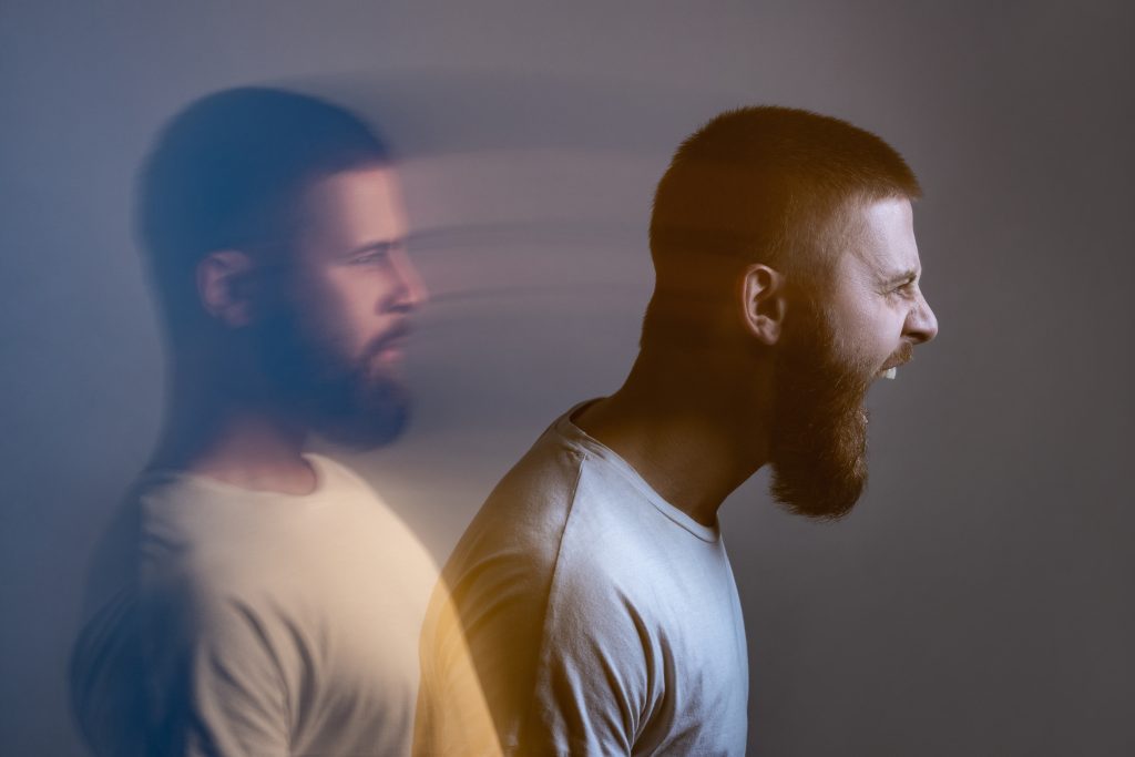 A man with a beard screams, his silhouette blurred behind him, conveying intense emotion and movement.
