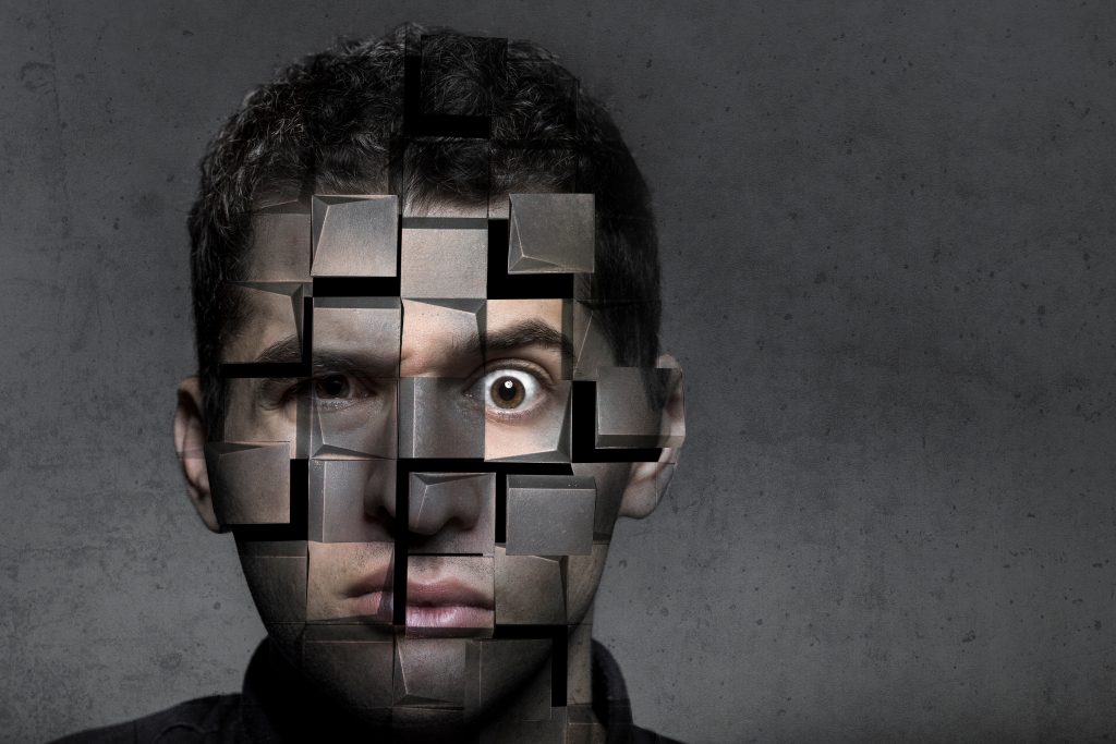 A man's face appears fragmented, with square pieces missing, revealing a stark gray background.