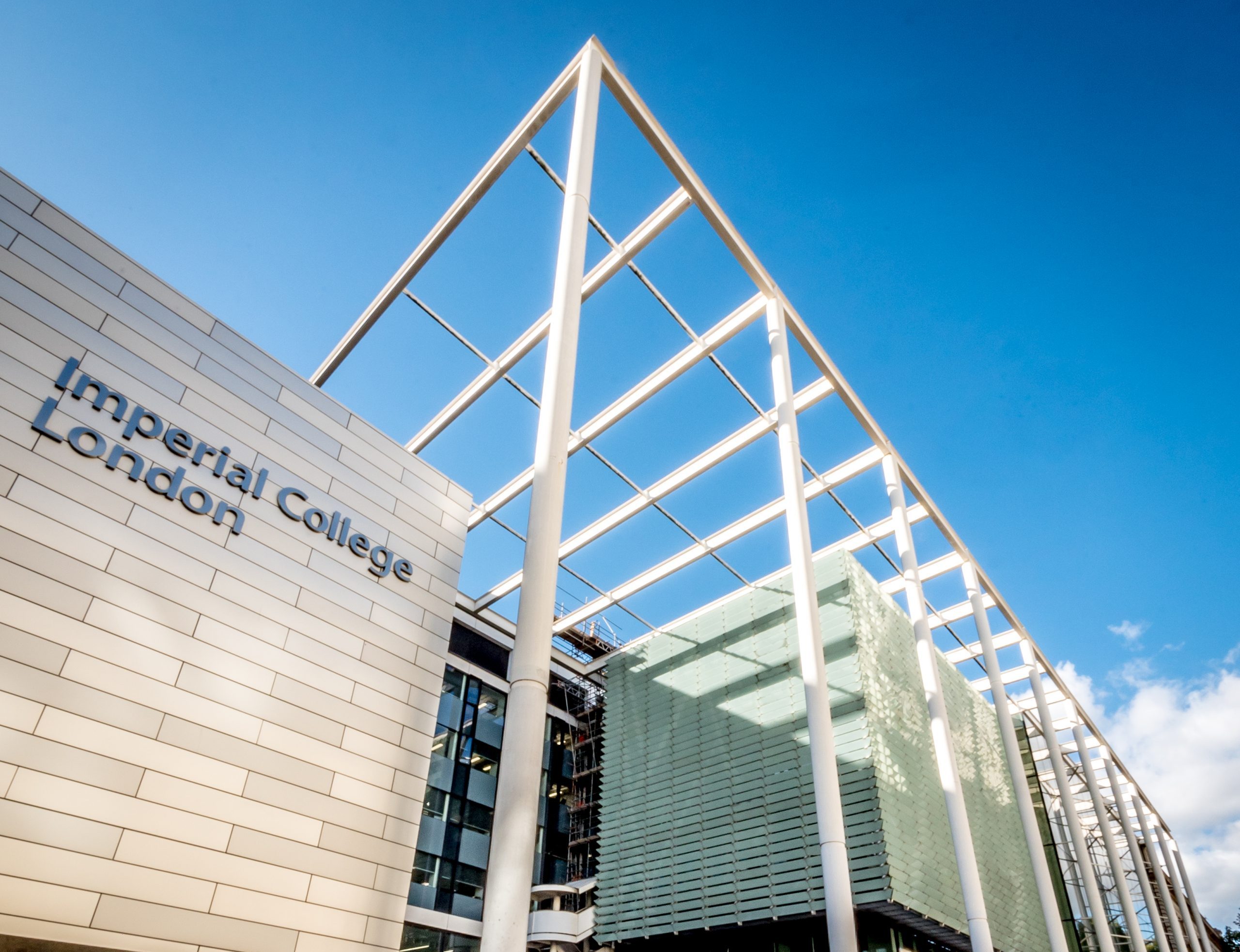 Modern architecture of Imperial College London, featuring a striking triangular roof against a clear blue sky.