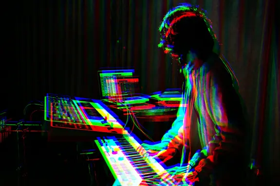 Musician playing a synthesizer with vibrant, distorted colors and a blurred motion effect.