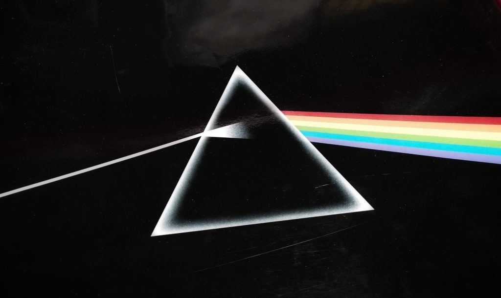Prism refracting light into a rainbow spectrum against a black background.