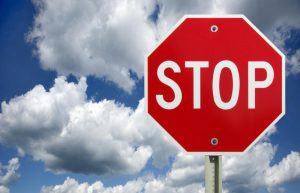 Red octagonal stop sign against a backdrop of blue sky and fluffy white clouds.