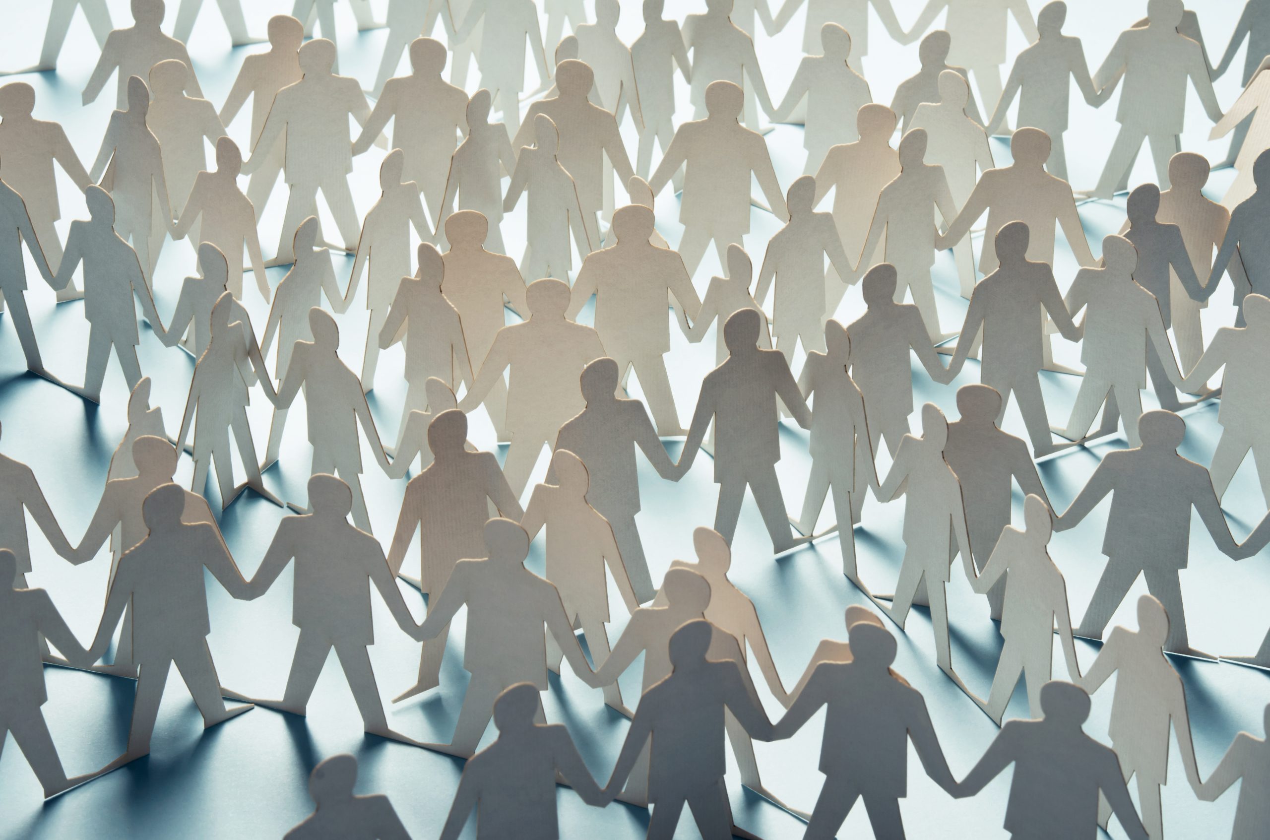 A sea of paper cutouts of people holding hands, symbolizing unity and connection.