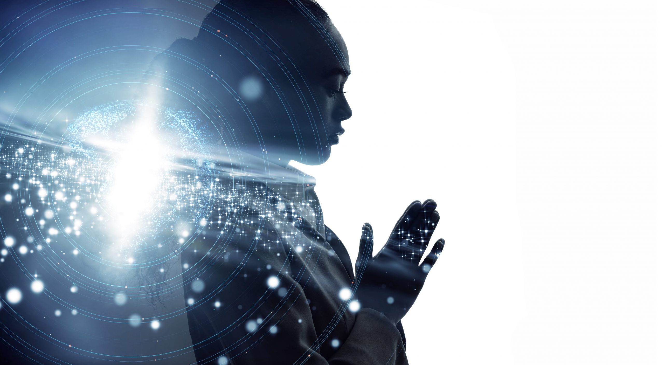 Silhouette of a person in prayer, surrounded by glowing particles and a bright light, evoking a sense of spirituality.