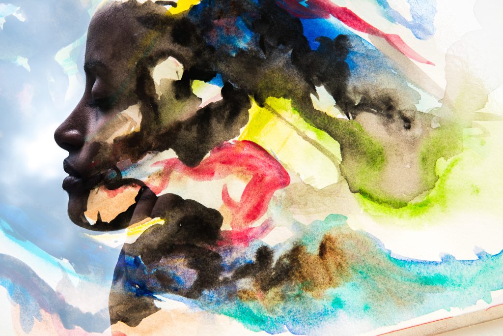 Silhouette of a woman blended with vibrant watercolor swirls in blues, yellows, and reds, creating a dreamlike effect.