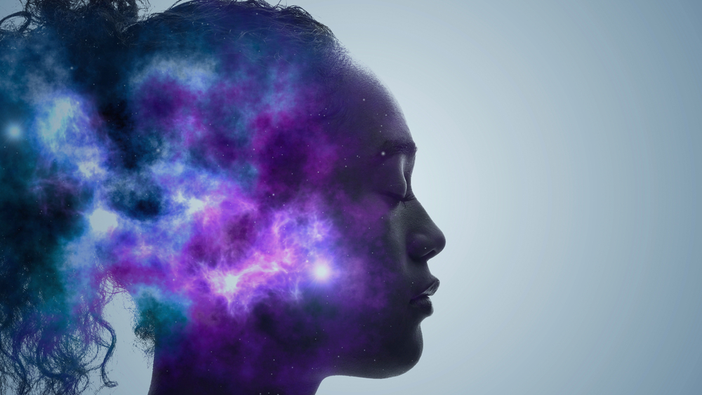 Silhouette of a woman with a cosmic nebula emerging from her head, blending colors of purple, blue, and white stars.