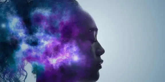 A silhouette of a woman with a cosmic nebula emerging from her head, blending colors of purple, blue, and stars.